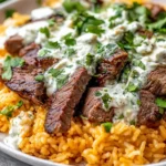 Steak & Queso Rice topped with sliced sirloin steak, creamy white queso sauce, and fresh cilantro over fluffy orange Tex-Mex rice.