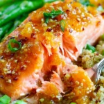 Apricot Dijon Glazed Salmon with glossy apricot-mustard sauce on a plate with quinoa, peas, and roasted asparagus.