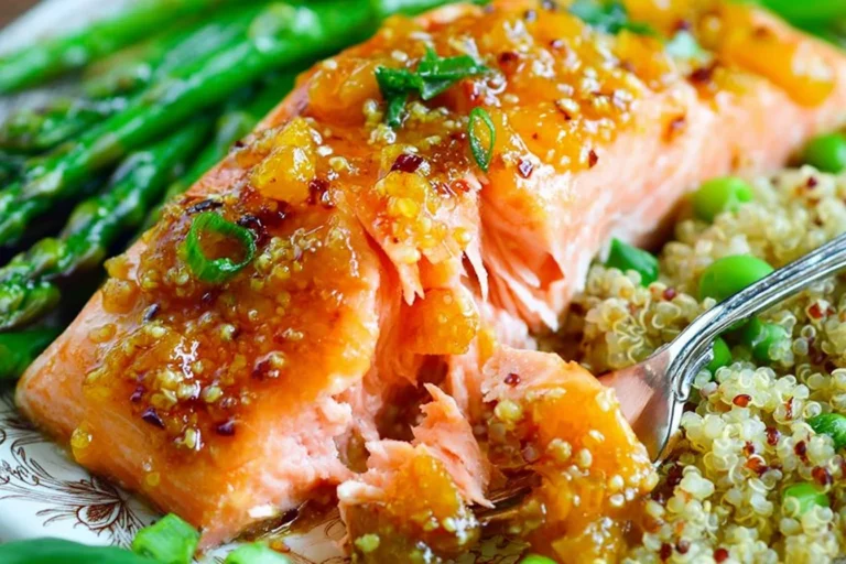 Apricot Dijon Glazed Salmon with glossy apricot-mustard sauce on a plate with quinoa, peas, and roasted asparagus.