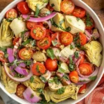 Artichoke Tomato Salad in a white bowl with cherry tomatoes, marinated artichoke hearts, red onion, fresh basil, and chickpeas.