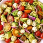 Avocado Salad Tomatoes Mozzarella Basil Pesto with cherry tomatoes, diced avocado, cucumber, red onion, and mozzarella pearls tossed in basil pesto.