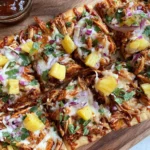 BBQ Chicken Pineapple Flatbread topped with shredded BBQ chicken, melted cheese, pineapple chunks, red onion, and cilantro on a crispy flatbread.