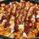 BBQ Chicken Potato Skillet in a cast-iron skillet with crispy cubed potatoes, saucy chicken, melted mozzarella, and extra BBQ drizzle.