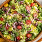 Big Classic Italian Salad piled high in a wooden bowl with crisp romaine, cherry tomatoes, kalamata olives, red onion, pepperoncini, and parmesan.