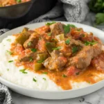 Hearty Grillades and Grits with tender Cajun beef stew, tomatoes, and green peppers spooned over creamy grits, finished with fresh parsley.