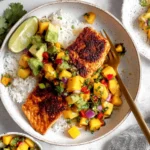 Cajun Salmon with Mango Salsa served over fluffy white rice with avocado, fresh cilantro, and lime wedges in a bright, colorful bowl.
