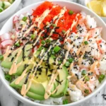 California Roll Sushi Bowls topped with imitation crab, avocado slices, cucumber, nori, sesame seeds, and spicy mayo over sushi rice.