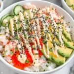 California Roll Sushi Bowls with sushi rice, imitation crab, cucumber, avocado, spicy mayo drizzle, and black sesame seeds.