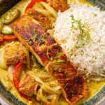 Caribbean-Style Coconut Curry Salmon served with fluffy white rice, sautéed peppers and onions, and creamy coconut curry sauce in a bowl.