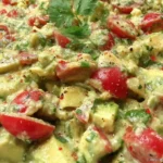 Avocado Crack Dip with cherry tomatoes, feta, parsley, and garlic, served creamy and chunky in a white bowl.