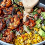 Grilled Shrimp Bowl with Avocado with charred shrimp, sweet corn salsa, chunky avocado, and creamy garlic sauce being poured over the top.