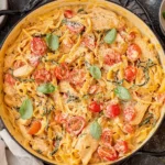 One Pot Chicken Margherita Pasta with Ricotta in a skillet with creamy tomato sauce, tender chicken, cherry tomatoes, parmesan, and fresh basil.
