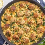 Tuscan Chicken Meatballs and Orzo in a skillet with creamy sauce, spinach, sun-dried tomatoes, and parmesan cheese