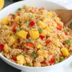 Mango Fried Rice in a white bowl with diced mango, red bell pepper, green onions, and lime wedges on the side.