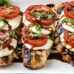 Grilled Chicken Caprese topped with fresh mozzarella, sliced tomatoes, basil, and balsamic glaze on a white platter.