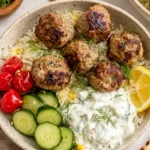 Gyro Bowls with juicy Greek-style meatballs, creamy tzatziki, lemon rice, sliced cucumbers, blistered tomatoes, and fresh dill in a ceramic bowl.