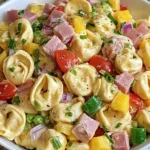 Hawaiian Tortellini Salad with cheese tortellini, ham, pineapple, bell peppers, peas, and creamy teriyaki dressing in a white bowl.