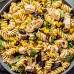High Protein BBQ Chicken Pasta Salad packed with rotini, grilled chicken, black beans, corn, cilantro, and creamy BBQ yogurt dressing in a large bowl.