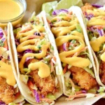 Honey Mustard Chicken Tacos with crispy chicken strips, crunchy broccoli slaw, and creamy honey mustard sauce drizzled on top.