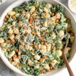 Overhead view of Kale Caesar Pasta Salad with rotini, chopped kale, crispy roasted chickpeas, and shaved parmesan in a large bowl.
