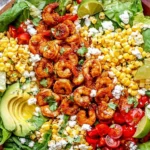 Honey Lime Shrimp Salad in a rustic bowl with honey-lime glazed shrimp, butter lettuce, sweet corn, cherry tomatoes, avocado, queso fresco, cilantro, and lime wedges.