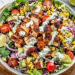 Mexican Grilled Chicken Salad in a large bowl with grilled chicken, black beans, corn, cherry tomatoes, red onion, avocado, and creamy avocado-cilantro dressing.