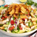 Santa Fe Chicken Salad piled high with taco-seasoned chicken, romaine, cherry tomatoes, red onion, avocado, cilantro, creamy dressing, and crunchy tortilla strips.