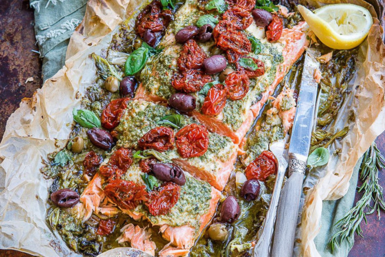 Mediterranean Salmon in Parchment Paper topped with pesto, sun-dried tomatoes, kalamata olives, capers, and fresh herbs, baked until flaky and juicy.