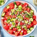Watermelon Cucumber Feta Salad with mint, basil, and crumbled feta in a bowl with honey-lime dressing