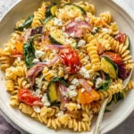 Roasted Veggie Pasta with Feta in a bowl with fusilli, roasted cherry tomatoes, zucchini, red onion, spinach, and crumbled feta.