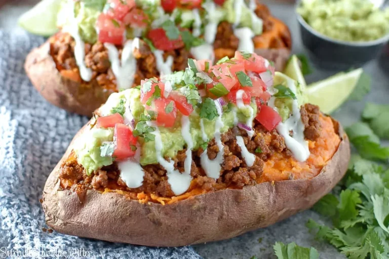 Taco Stuffed Sweet Potatoes topped with seasoned taco beef, creamy guacamole, pico de gallo, and a sour cream drizzle.