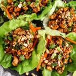 Thai Chicken Lettuce Wraps piled with sweet chili ground chicken, chopped cashews, scallions, cilantro, and shredded carrots in butter lettuce cups.