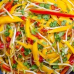 Thai Mango Salad in a blue bowl with mango strips, bean sprouts, red bell pepper, cilantro, and lime-chili dressing.