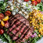Balsamic Steak Gorgonzola Salad with Grilled Corn served with sliced balsamic-marinated steak, grilled corn, Gorgonzola cheese, cherry tomatoes, red onion, and fresh mixed greens.