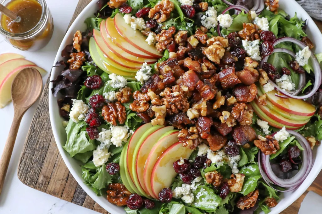 Blue Cheese Apple Walnut Salad with crisp apple slices, candied walnuts, bacon, blue cheese crumbles, dried cranberries, and mixed greens topped with maple vinaigrette.
