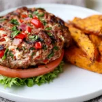 Mediterranean Stuffed Burgers served bunless with feta cheese, spinach, bell peppers, fresh herbs, lettuce, tomato, and roasted sweet potato wedges