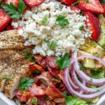 Chicken Strawberry Salad Bowls with grilled chicken, fresh strawberries, bacon, avocado, feta cheese, and romaine lettuce in a healthy meal prep bowl.