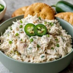 Copycat Jalapeño Hollychicken Salad in a serving bowl topped with fresh jalapeño slices and green onions, surrounded by crackers for a creamy, spicy chicken salad recipe.