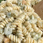 Dill Pickle Pasta Salad in a bowl with creamy dill dressing, rotini, chopped pickles, and Colby Jack cheese.