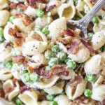 Spoonful of Creamy Pasta Salad with shell pasta, peas, crispy bacon, and creamy dressing, served in a bowl.