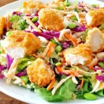 Applebee’s Oriental Chicken Salad with crispy breaded chicken, romaine, red cabbage, shredded carrots, and crunchy toppings on a white plate.