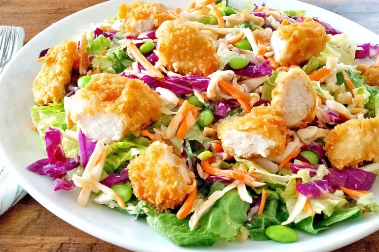 Applebee’s Oriental Chicken Salad with crispy breaded chicken, romaine, red cabbage, shredded carrots, and crunchy toppings on a white plate.