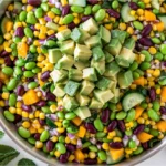Colorful Edamame Mango Salad topped with creamy avocado, black beans, sweet corn, cucumber, and red onion in a large serving bowl.