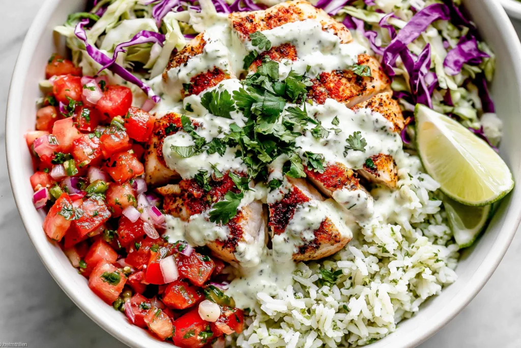 Mahi Mahi Taco Bowls loaded with seasoned mahi mahi, cilantro lime rice, fresh pico de gallo, crunchy cabbage slaw, cilantro lime crema, and lime wedges in a healthy taco bowl.
