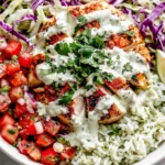 Mahi Mahi Taco Bowls loaded with seasoned mahi mahi, cilantro lime rice, fresh pico de gallo, crunchy cabbage slaw, cilantro lime crema, and lime wedges in a healthy taco bowl.