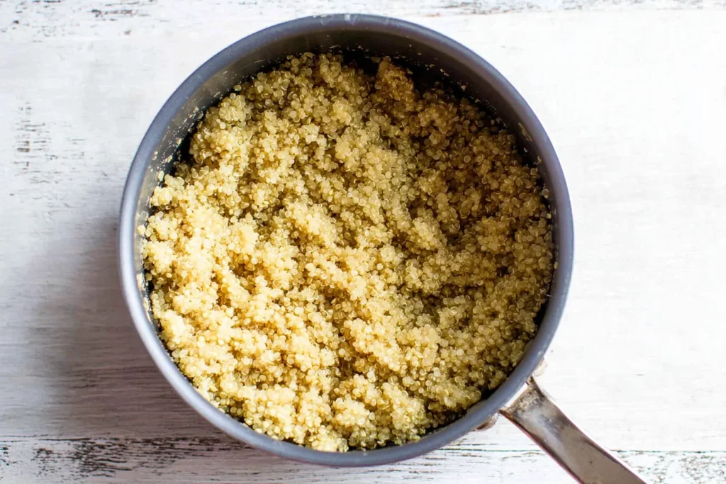 Cooked quinoa cooling in a saucepan for Fiesta Mango Quinoa Salad, ready to fluff and mix with mango, beans, and veggies.