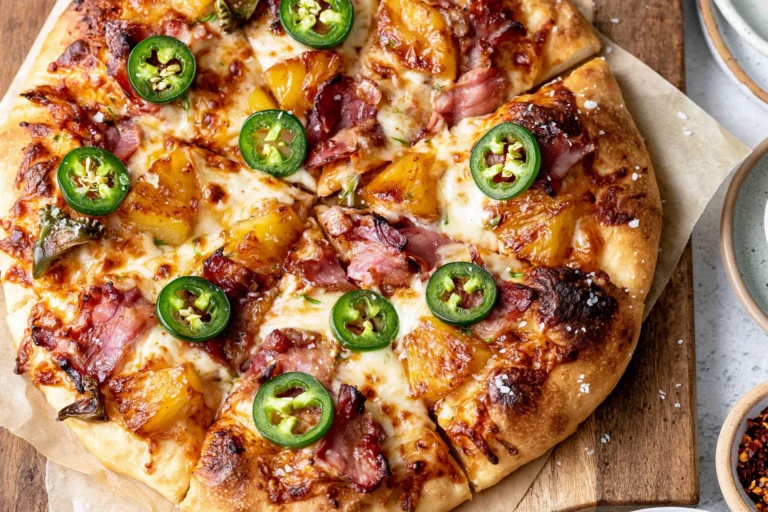 Hawaiian pizza topped with caramelized pineapple, crispy bacon, prosciutto, melted mozzarella, and fresh jalapeños on a golden homemade crust.