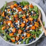 Honey Sweet Potato Summer Salad with roasted sweet potato cubes, fresh blueberries, arugula, goat cheese, pepitas, and honey lemon vinaigrette.