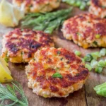 Chicken Burgers with Avocado Corn Salsa on a wooden board with golden-browned patties, sliced avocado, scallions, and lime wedges.