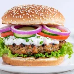 Greek Feta Turkey Burgers served on a sesame seed bun with tzatziki sauce, cucumber slices, tomatoes, red onion, and crisp lettuce for a healthy Mediterranean-inspired meal.